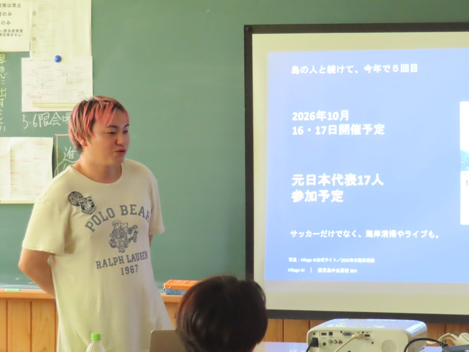 種子島 BiG ViSiON 2026の開催予定（10月16・17日、元日本代表17人参加予定）を投影しながら話す里洋平